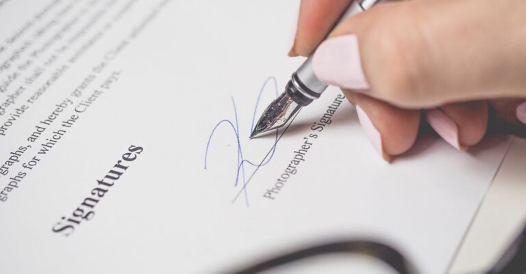 Nahaufnahme einer Hand, die einen Vertrag unterschreibt, mit Stift und eleganter Handschrift.