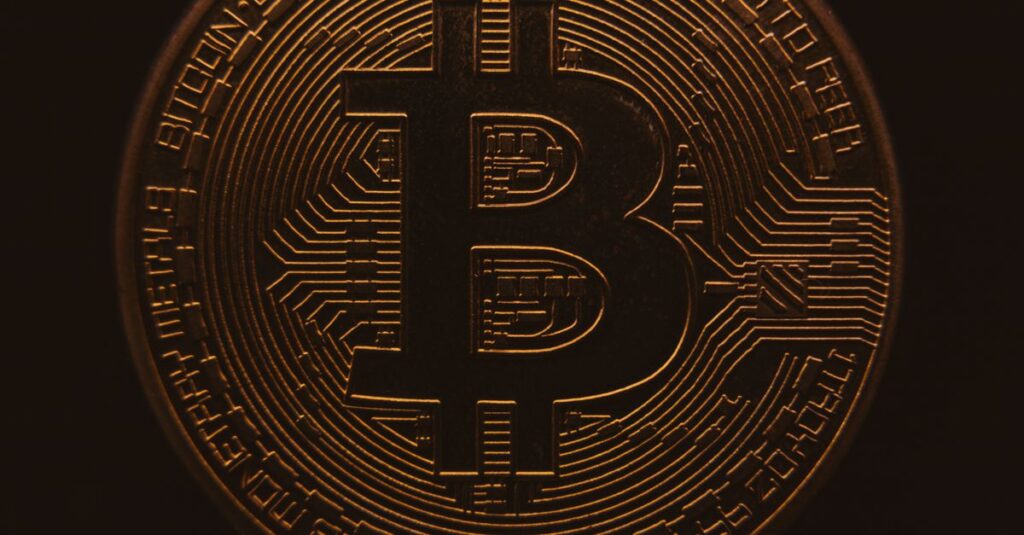 Nahansicht einer Bitcoin-Münze, die ihr komplexes digitales Design in einer warmen, dunklen Atmosphäre zeigt.