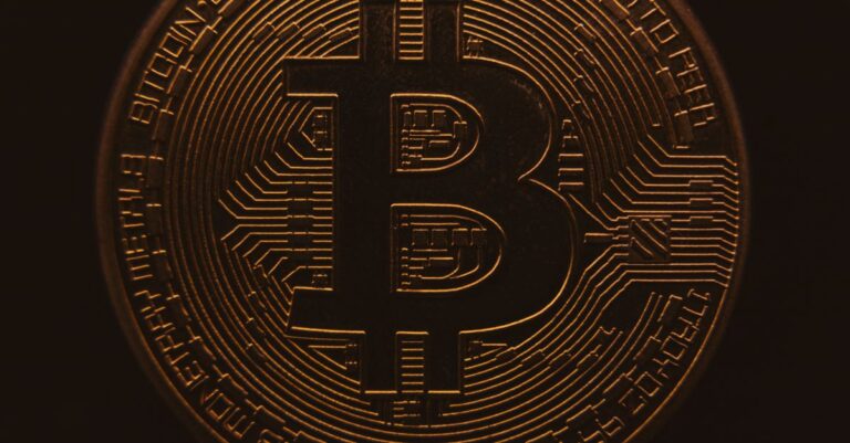 Nahansicht einer Bitcoin-Münze, die ihr komplexes digitales Design in einer warmen, dunklen Atmosphäre zeigt.
