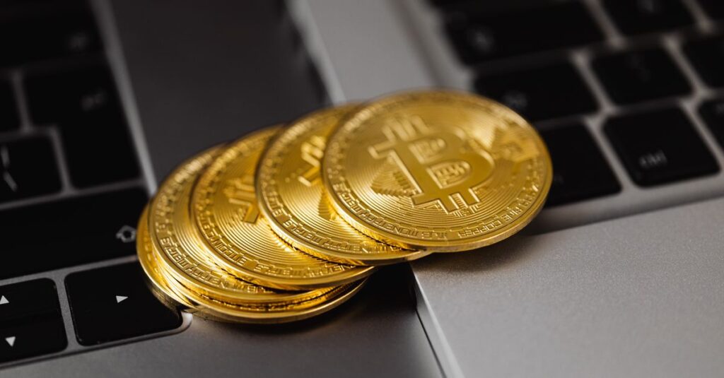Nahaufnahme von goldenen Bitcoins auf einer Laptop-Tastatur, die digitale Währung und Reichtum repräsentiert.